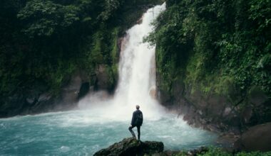 man standing on cliff near falls