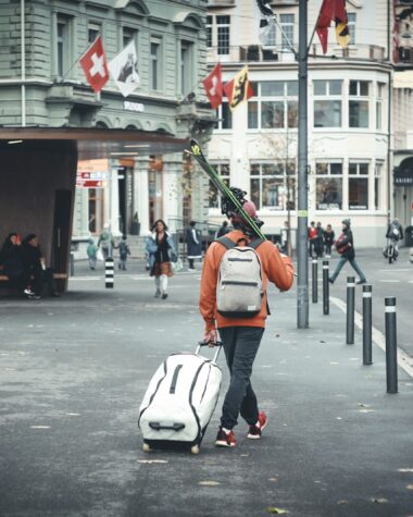 man in orange jacket and black pants with white helmet riding on white and black motor