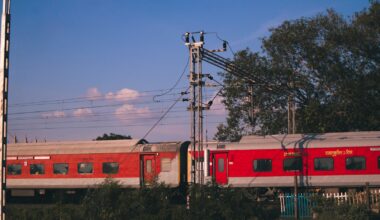 red and white train on rail under blue sky during daytime