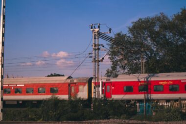 red and white train on rail under blue sky during daytime
