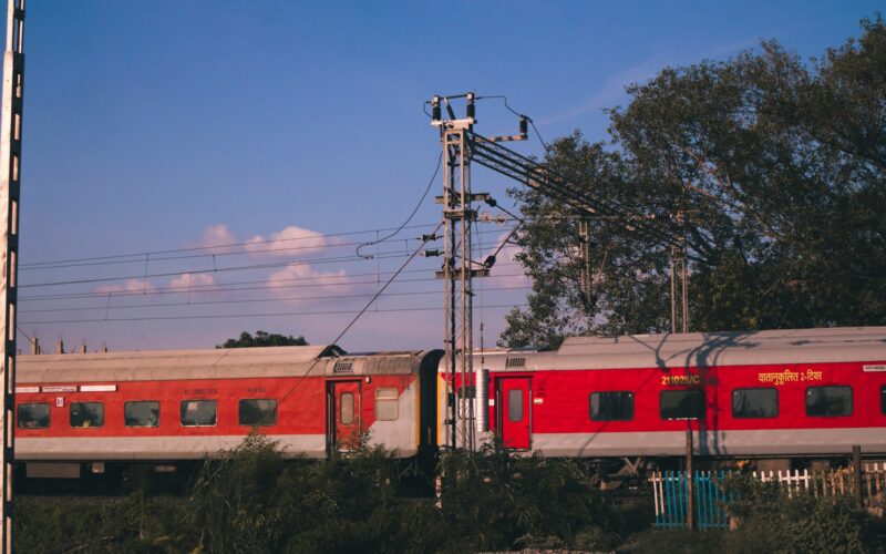 red and white train on rail under blue sky during daytime