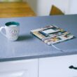 gray and white ceramic mug beside multicolored covered book