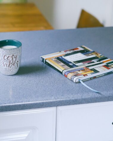 gray and white ceramic mug beside multicolored covered book
