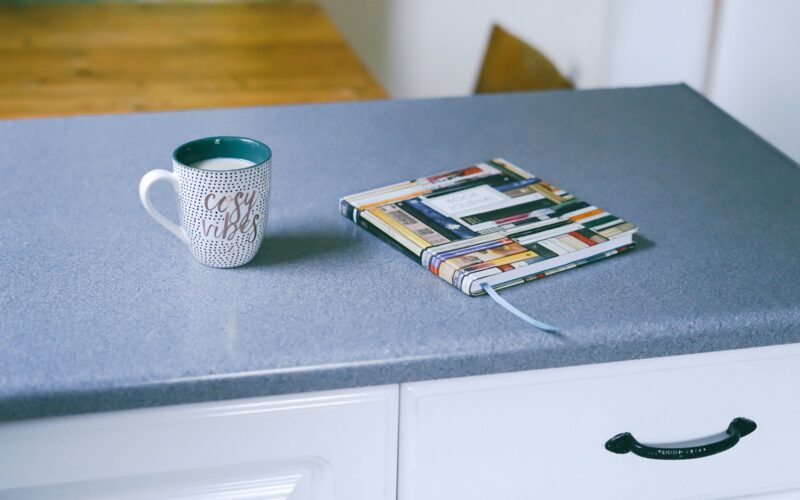 gray and white ceramic mug beside multicolored covered book