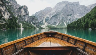 brown wooden boat moving towards the mountain