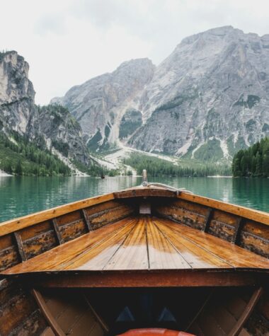brown wooden boat moving towards the mountain