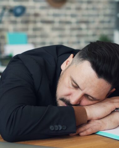 a man leaning his head on his desk