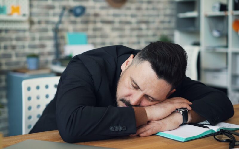 a man leaning his head on his desk